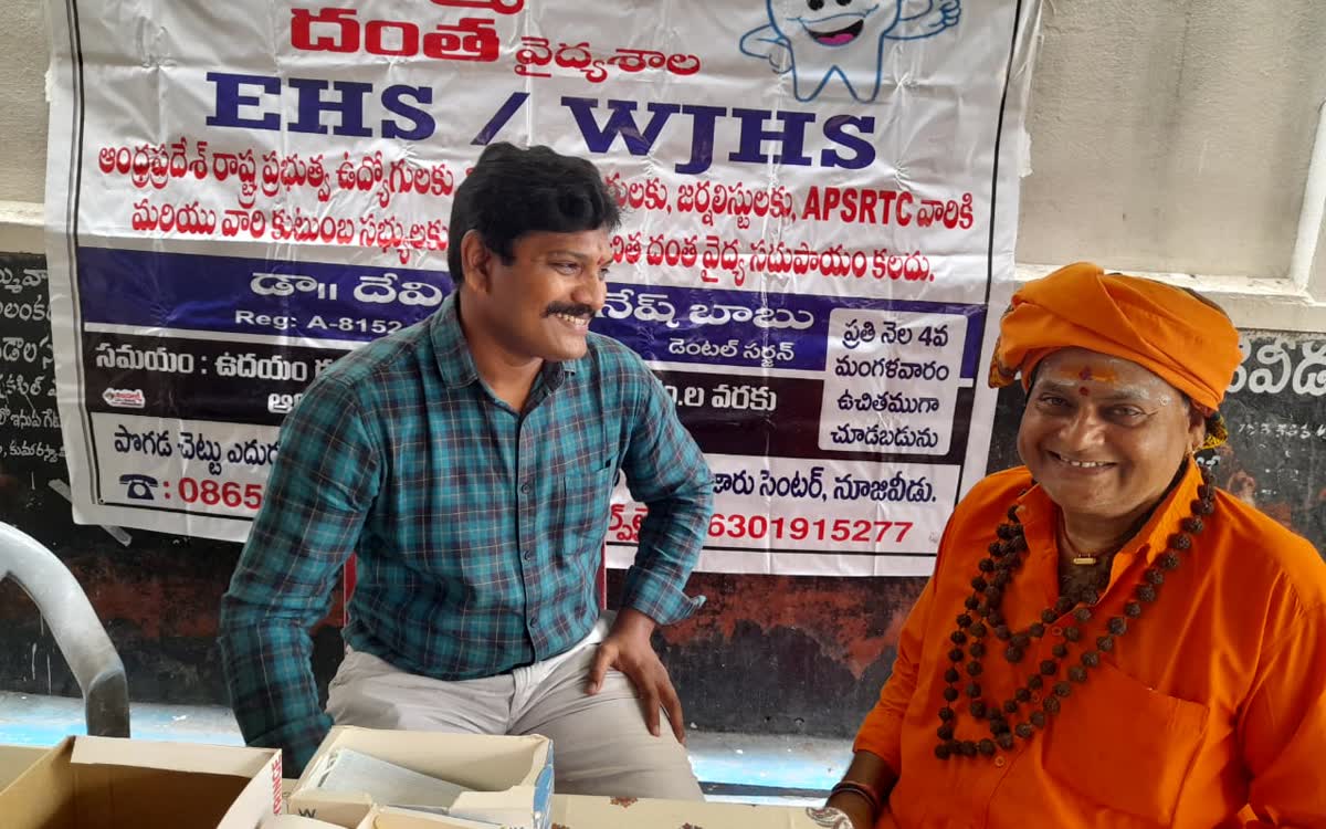 Guruji seated with the visiting dentist beneath the dental camp banner
