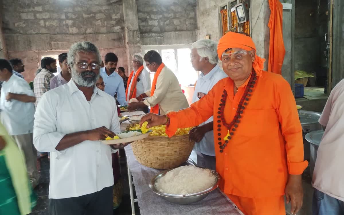 Guruji handing food from a large basket to a man holding out his plate