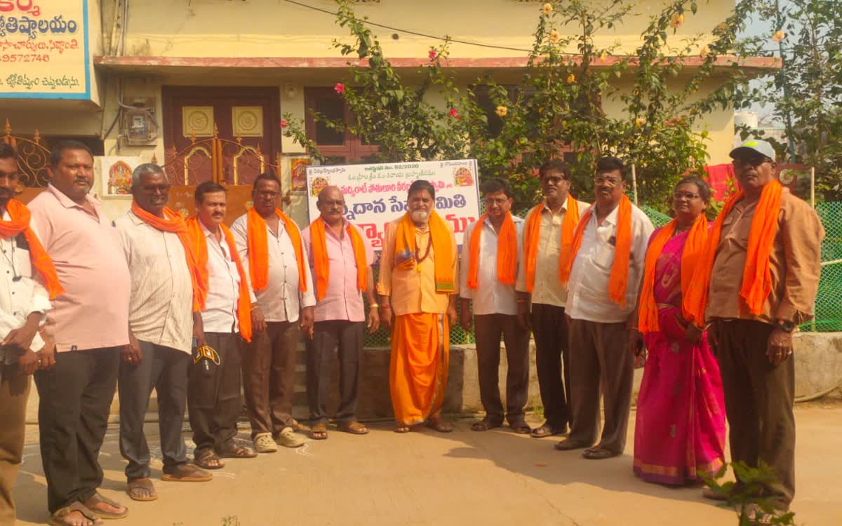 Guruji standing with a row of volunteers in orange scarves outside the Samithi office