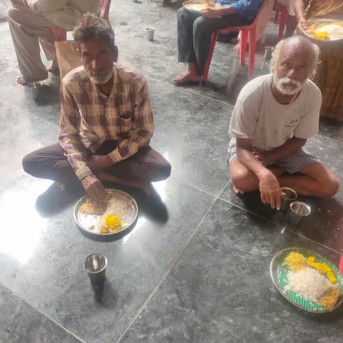 Two men seated on the floor with their meals